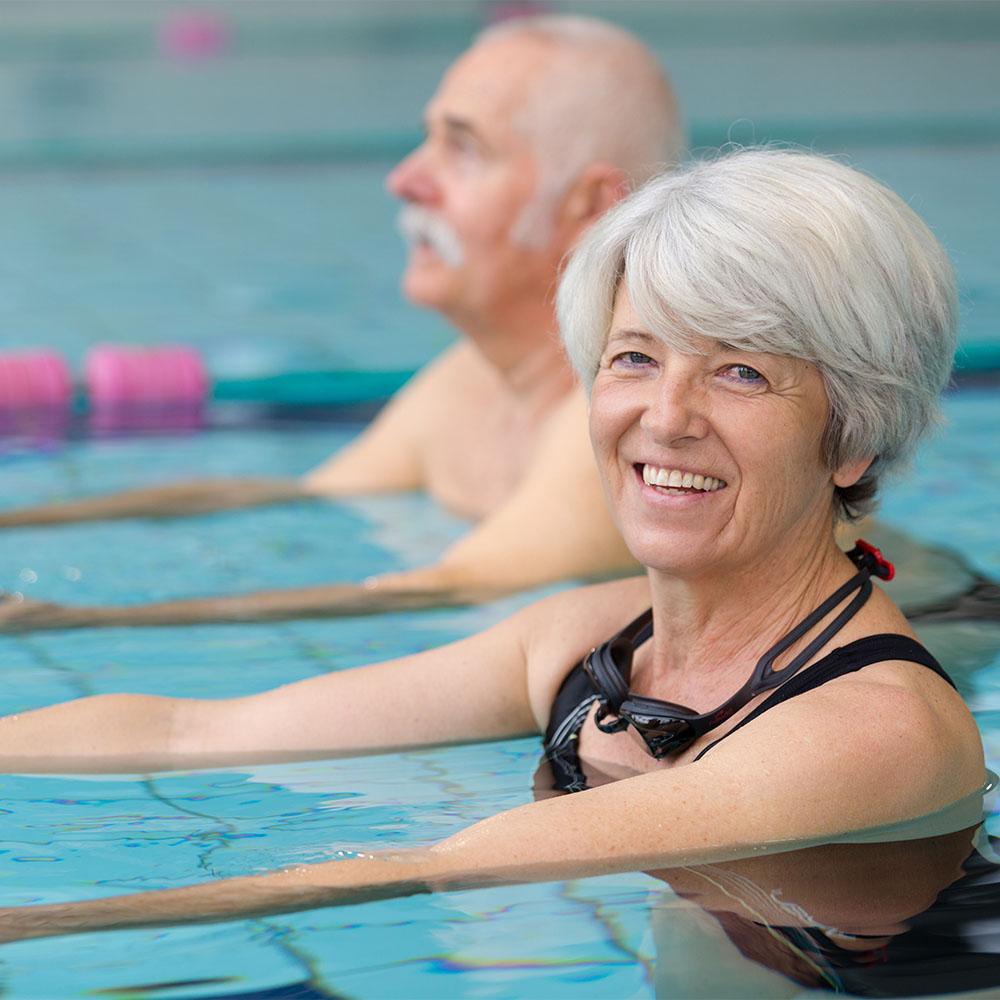 Two older people participating in aqua fitness class